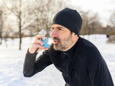 Mężczyzna chory na astmę używa inhalatora po wysiłku fizycznym.