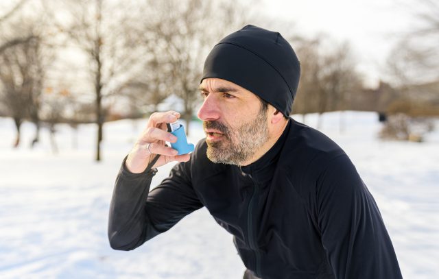 Mężczyzna chory na astmę używa inhalatora po wysiłku fizycznym.