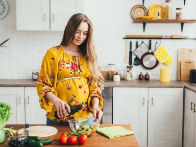 Kobieta w ciąży robiąca posiłek w kuchni.